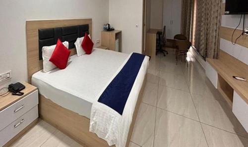 a bedroom with a large bed with red and blue pillows at FabHotel Prime Anika Suites in Hyderabad