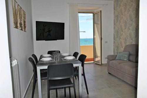a dining room with a table and chairs and a couch at Brezza di mare appartamento fronte spiaggia in Formia