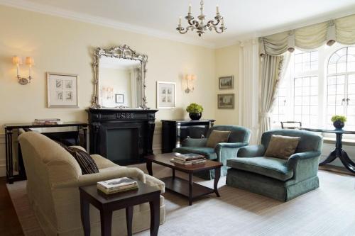 a living room with two chairs and a fireplace at The Connaught, Maybourne in London