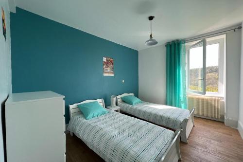 um quarto com duas camas e uma parede azul em Les Gites de Louisette 1886 em Ébreuil