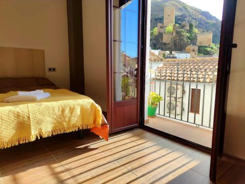 カソルラにあるEncantos de Cazorlaのベッドルーム1室(ベッド1台付)、バルコニーへのドアが備わります。