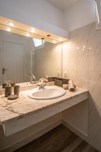 une salle de bain avec un lavabo et un grand miroir dans l'établissement Les quatres loges, à Aix-en-Provence