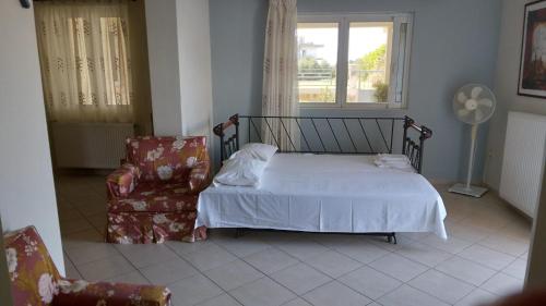 um quarto com uma cama, uma cadeira e uma janela em HOLIDAYS APARTMENT ΜΕΣΣΗΝΗ em Messini