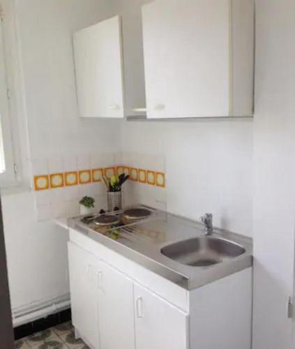 a white kitchen with a sink and white cabinets at Apt T3 - 3 Min du Futuroscope in Chasseneuil-du-Poitou