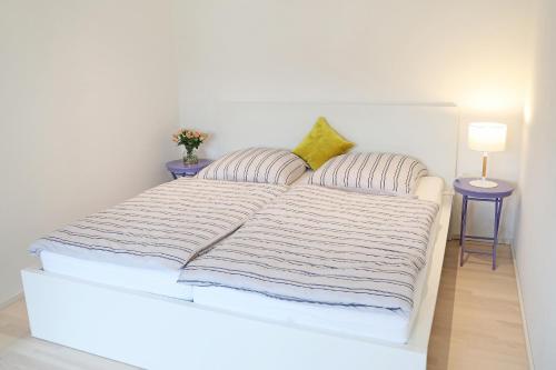 un letto bianco con due cuscini e due tavoli di Appartement Burgblick a Harburg