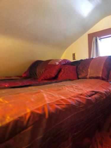 a bed with an orange comforter in a bedroom at chezbevet in Woodstock