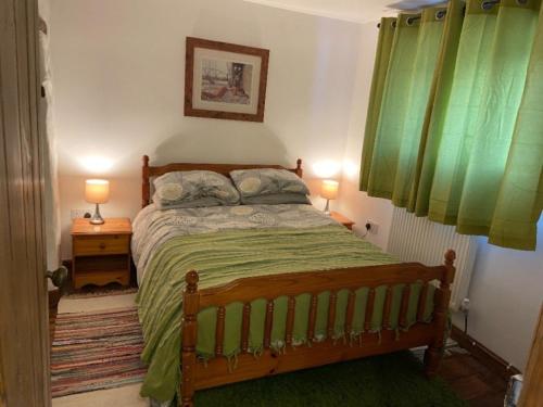 a bedroom with a bed with green sheets and two lamps at Forest Hill View in Cinderford
