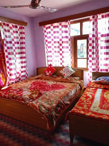 a bedroom with two beds with red and white curtains at Queen Palace guest house in Srinagar