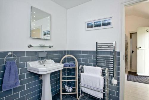 Baño de azulejos azules con lavabo y espejo en Hill Head Cottage en Saint Columb Major