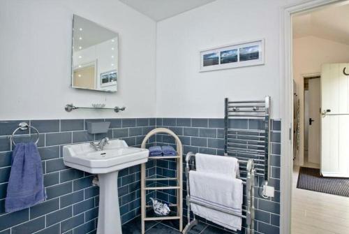 bagno piastrellato blu con lavandino e specchio di Hill Head Cottage a Saint Columb Major
