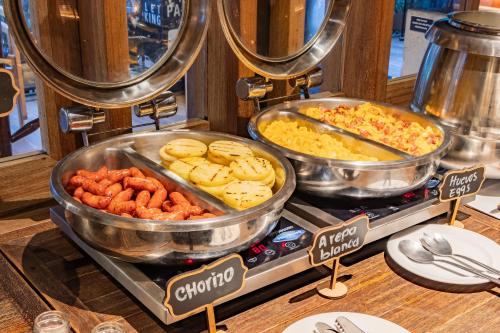 a buffet with many different types of food in pans at GHL Bioxury Hotel in Bogotá