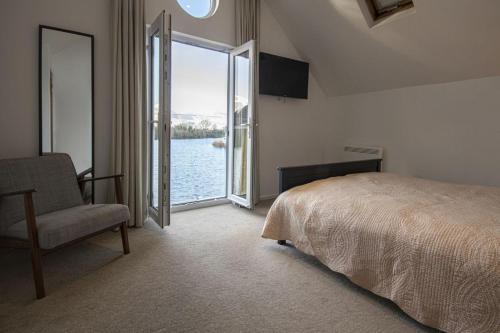 a bedroom with a bed and a chair and a large window at Spring Lake 41, Lapwing Lake Lodge - P in South Cerney