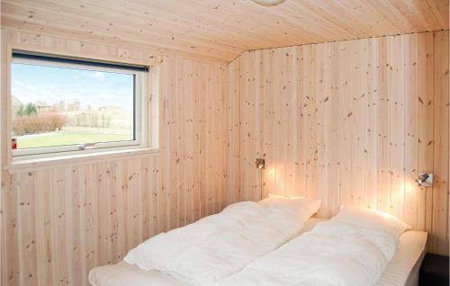 a bedroom with a wooden wall with a window at 4 Bedroom Awesome Home In Rnde in Rønde