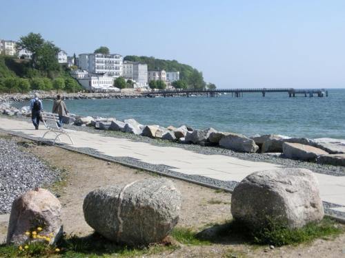 a person walking on a sidewalk next to the water at Villa Melanie in Sassnitz