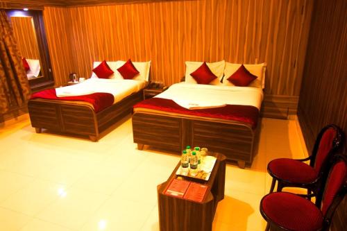 Cette chambre d'hôtel comprend deux lits, une table et des chaises. dans l'établissement JJs PARK INN, à Chennai