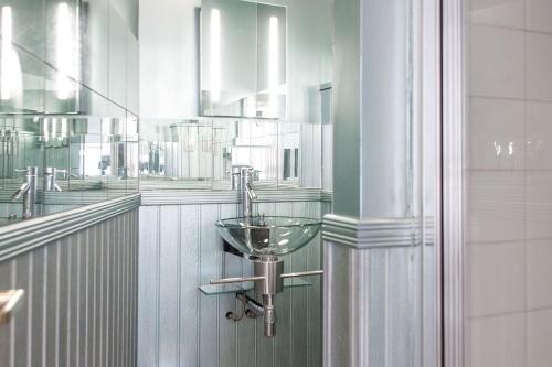 a bathroom with a sink and mirrors on the wall at Isis Lakes 09, ArtHouse in South Cerney