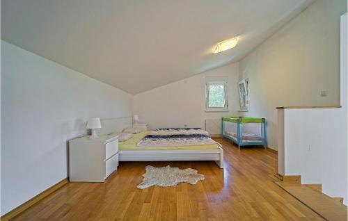 a white bedroom with a bed and a wooden floor at Awesome Home In Donji Zvecaj With Wifi in Donji Zvečaj