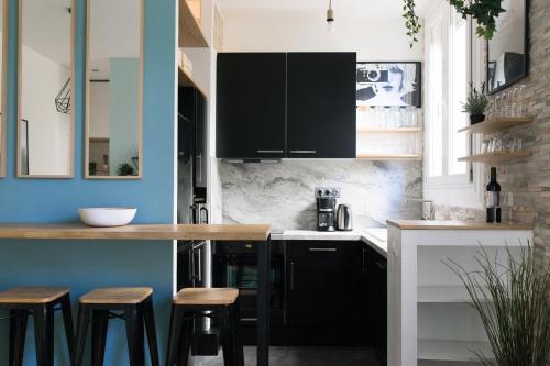 une cuisine avec des placards et des tabourets en noir et blanc dans l'établissement Sleep In Montpellier, cosy, central, 5 ch, 10p, Tram L1, 2,3 & 4, à Montpellier