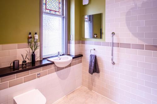 a bathroom with a sink and a toilet and a window at Eton House - Self Check-In Serviced Studios & Rooms in Yeovil