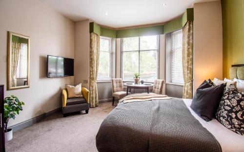 a bedroom with a bed and a table and windows at Eton House in Yeovil