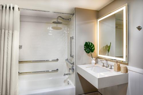 a white bathroom with a sink and a mirror at Ashore Resort & Beach Club in Ocean City