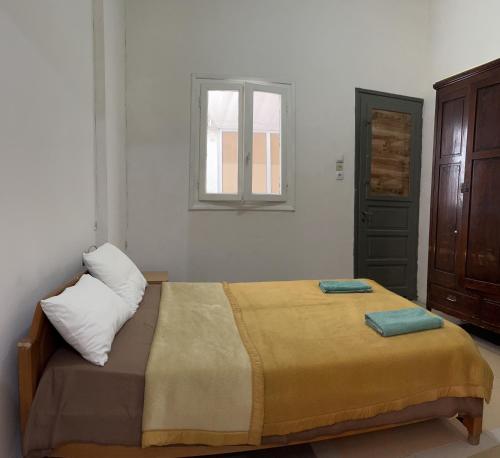 a bedroom with a bed with two pillows and a window at Traditional Lemon House near to Pireaus Port in Piraeus