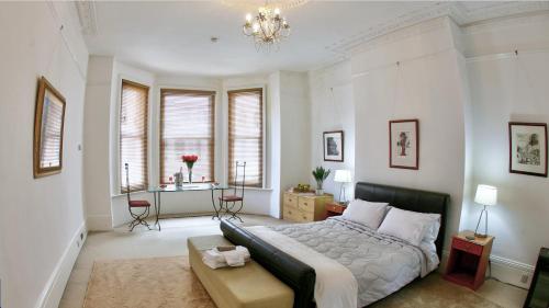 a bedroom with a bed and a table and windows at Burlington Palace Eastbourne Seafront Villa with Garden. in Eastbourne