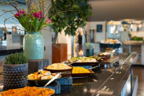 a buffet line with plates of food and a vase of flowers at Quality Hotel Winn Haninge in Haninge