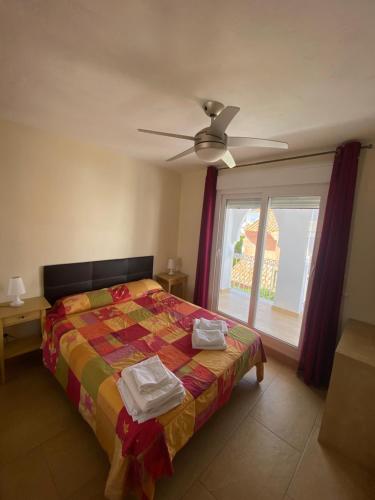 a bedroom with a bed with a ceiling fan and a window at La Tahona 27-H in Zahara de los Atunes