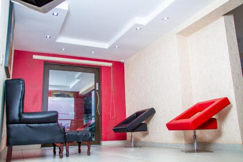 a waiting room with three chairs and a red wall at Kliprivier Guest House in Tokoza