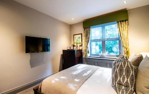 a bedroom with a bed and a tv and a window at Eton House - Self Check-In, Ensuite Rooms & Self-Catering Studios in Yeovil