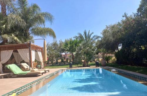 einen Pool in einem Garten mit Palmen in der Unterkunft Villa rouge in Marrakesch