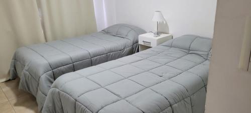 two beds in a room with a lamp on a table at Apartamento en el centro de Banfield in Banfield