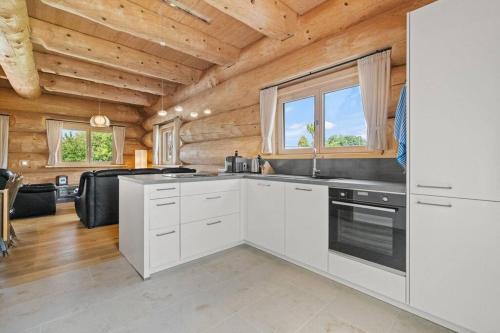 a kitchen with white cabinets and wood ceilings at Blockhaus am Pfrunger Ried in Riedhausen