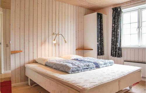 a bed in a room with wooden walls and a window at Awesome Home In Tranekr With 4 Bedrooms And Sauna in Hou
