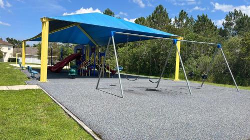 a playground with a blue and yellow canopy and swings at Close to Disney. Big house with backyard in Orlando