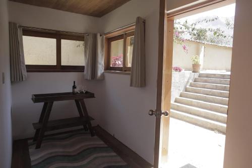 a room with a door and a table and stairs at Casafranca in Ollantaytambo