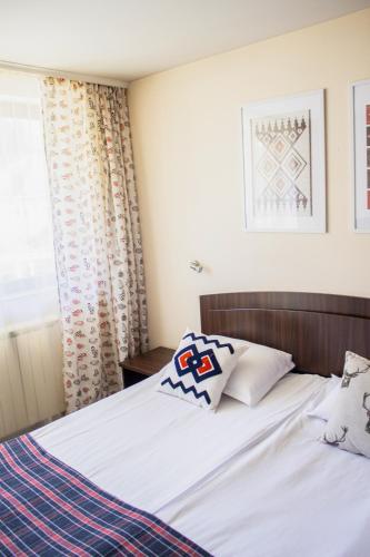 a bedroom with a bed with white sheets and pillows at Meteor Family Hotel in Chepelare