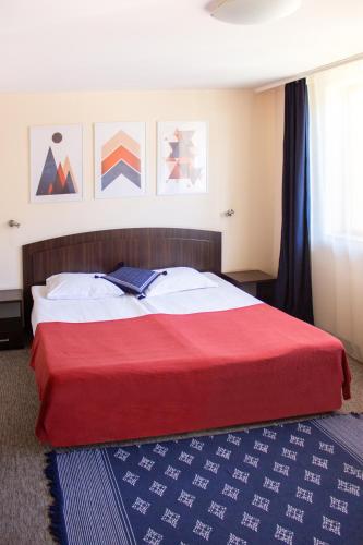 a bedroom with a red bed with a blue rug at Meteor Family Hotel in Chepelare