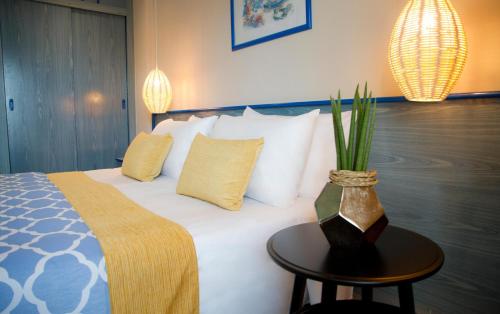 a bedroom with a bed with white pillows and a table at ALEGRIA Fenals Mar in Lloret de Mar
