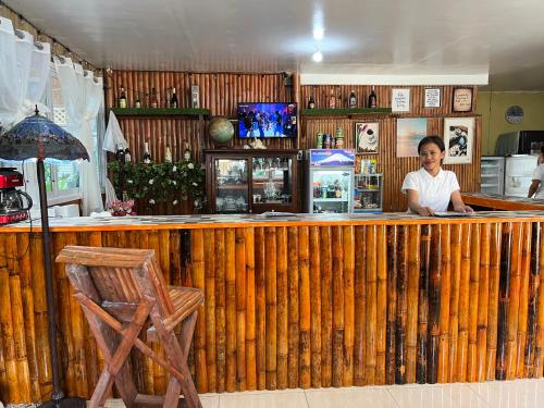 une femme debout derrière un bar en bois dans un restaurant dans l'établissement Treasure Cove Apartment, à Carles