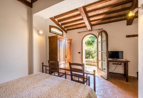 a bedroom with a bed and a desk and a window at Glicine Apartment Podere Giardino in Montalcino