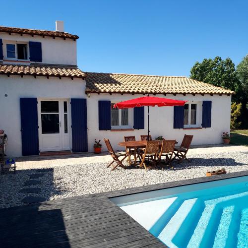 une maison avec une table, un parasol et une piscine dans l'établissement Les Mazets du Paty, à Albaron