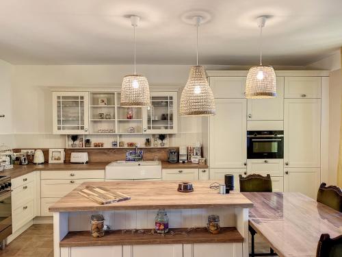 une cuisine avec des armoires blanches et un comptoir en bois dans l'établissement Maison de vacances au cœur de la nature, à Sully