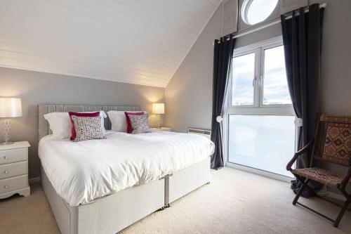 a bedroom with a bed and a large window at Spring Lake 19, The Lake House in South Cerney
