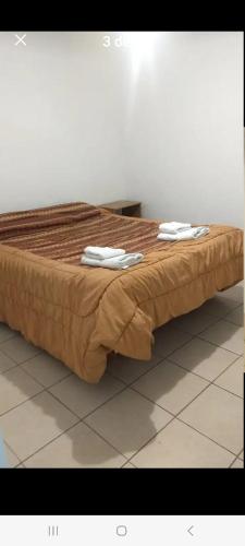 uma cama com lençóis castanhos e toalhas brancas em Deptos San Luis em San Rafael