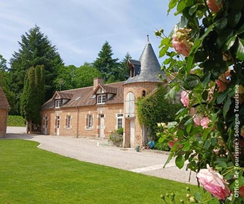 een oud bakstenen huis met een torentje bij Le pigeonnier de la Farge in Chaumont-sur-Tharonne