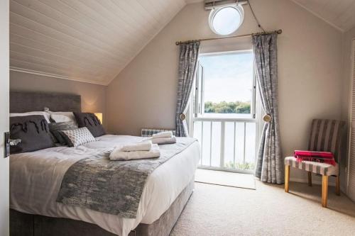 ein Schlafzimmer mit einem großen Bett und einem großen Fenster in der Unterkunft Spring Lake 14, Lakeside Retreat in South Cerney