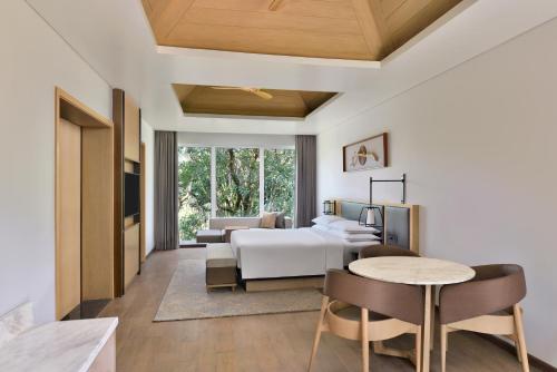 Coorg Marriott Resort & Spa في ماديكيري: غرفة نوم بسرير وطاولة وكراسي