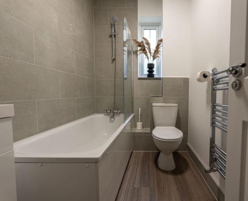 a bathroom with a tub and a toilet and a sink at Elms House, sleeps 5, free parking in Reading